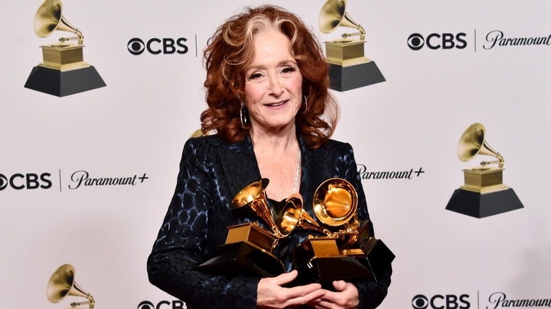 Bonnie Raitt wears a black and blue jacket with large hoop earrings and her signature gray streak against her bright red curls at the 65th GRAMMY Awards at Crypto.com Arena in Los Angeles, California in February 2023.