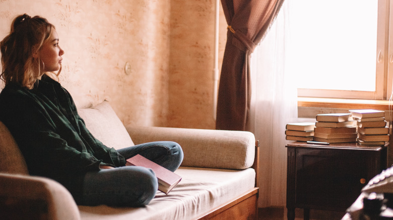 Young woman sad near book pile