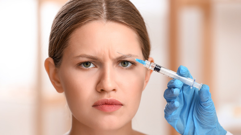 Frowning model receiving injection in forehead