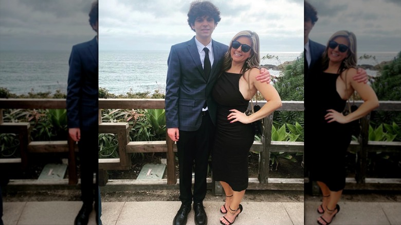 Brandi Passante wearing a black dress and standing next to her son in front of the ocean