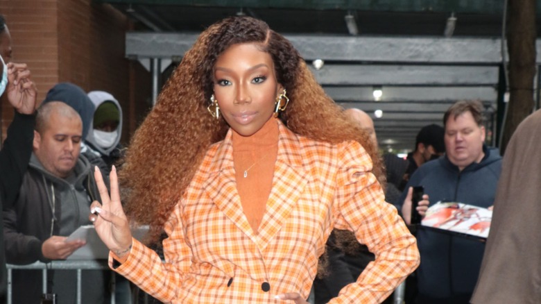 Brandy in a plaid blazer and voluminous curly hair