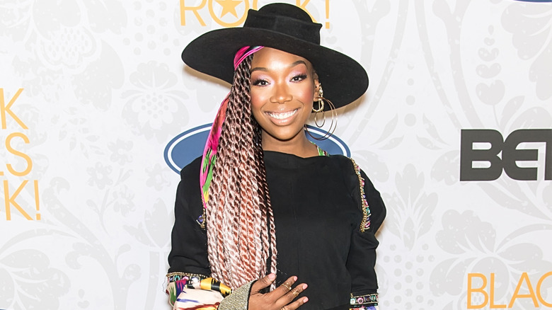 Brandy with long multicolored braids and a black wide-brimmed hat