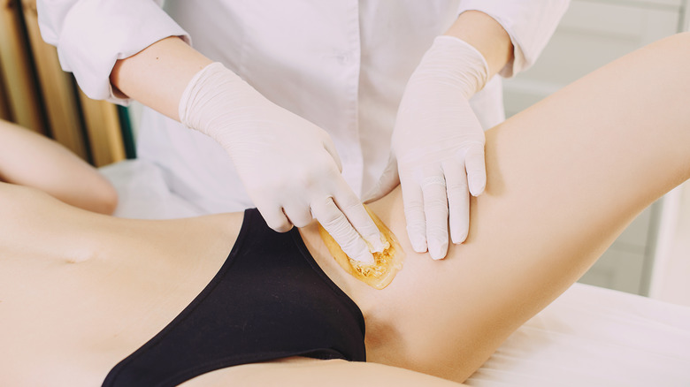 Technician performing bikini wax on woman