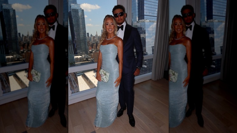 Brittany Mahomes and Patrick Mahomes pose together in front of a window overlooking the NYC skyline.