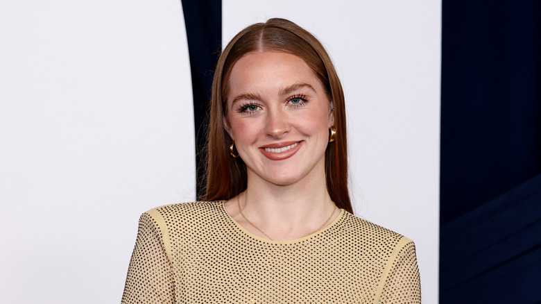 Brooke Shields' daughter Rowan Henchy wearing a gold dress and neutral makeup on a red carpet.