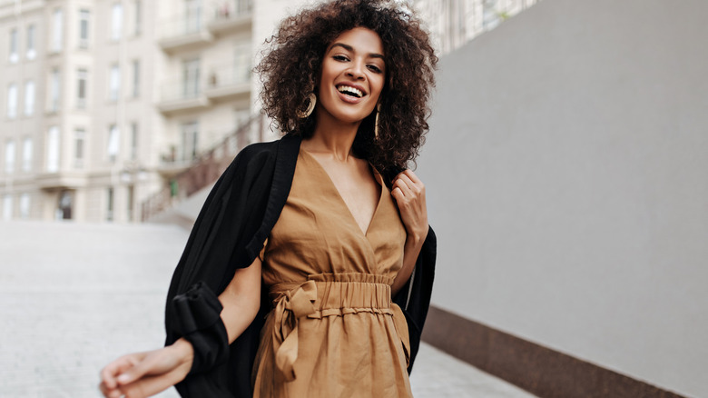 Woman poses wearing brown dress and black sweater 