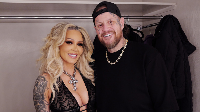 Bunnie XO and Jelly Roll smile while wearing black outfits and chain necklaces