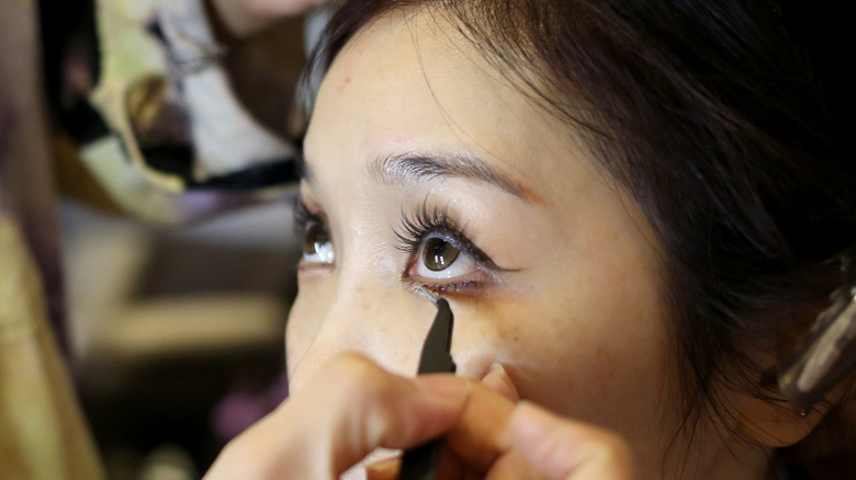 Asian person applying makeup