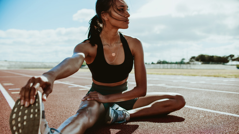 woman stretching legs on track