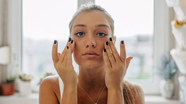Woman applying skincare on face