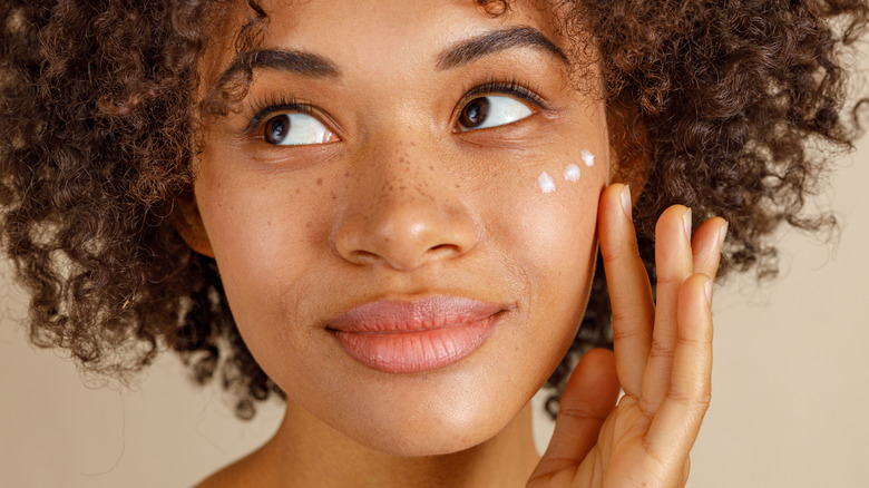 Woman applying cream to face