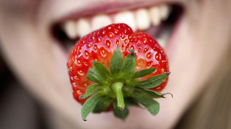Closeup of strawberry in woman's mouth