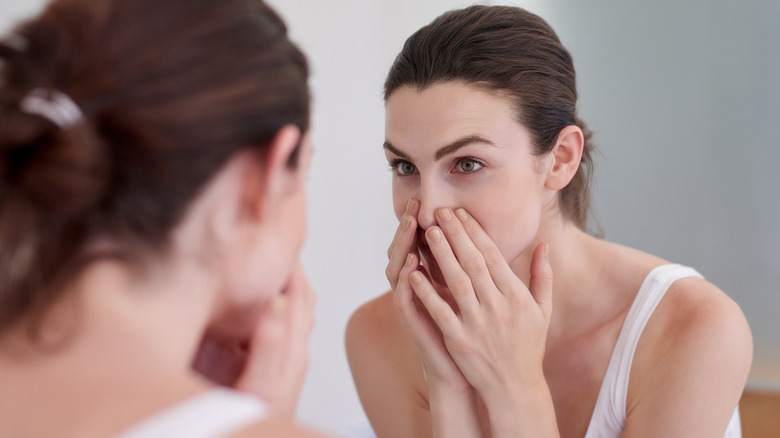 woman examining pores in mirror