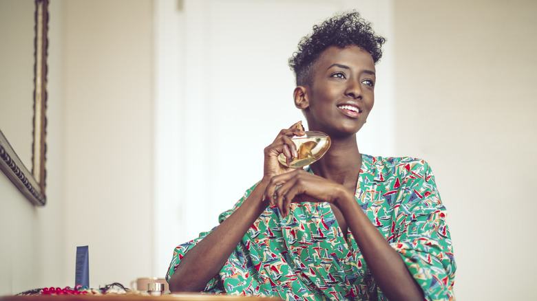 woman applying perfume at home