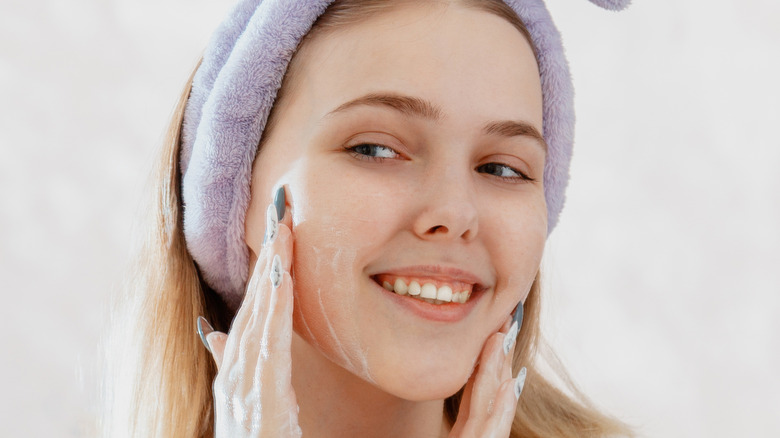 female wearing a headband apply skincare product on her face