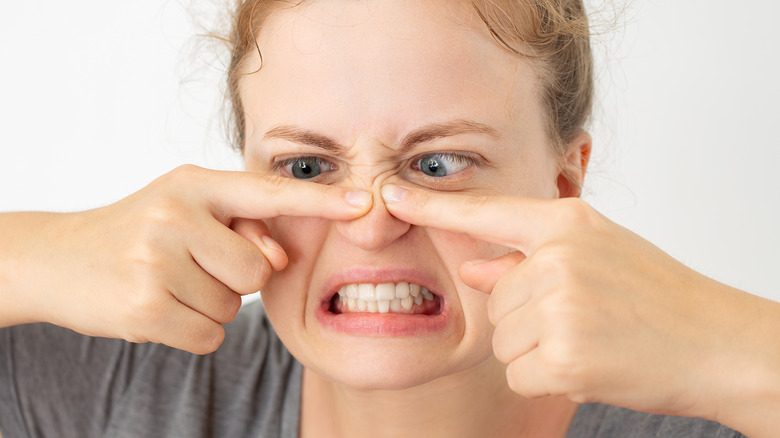 female trying to squeeze a pimple on her nose