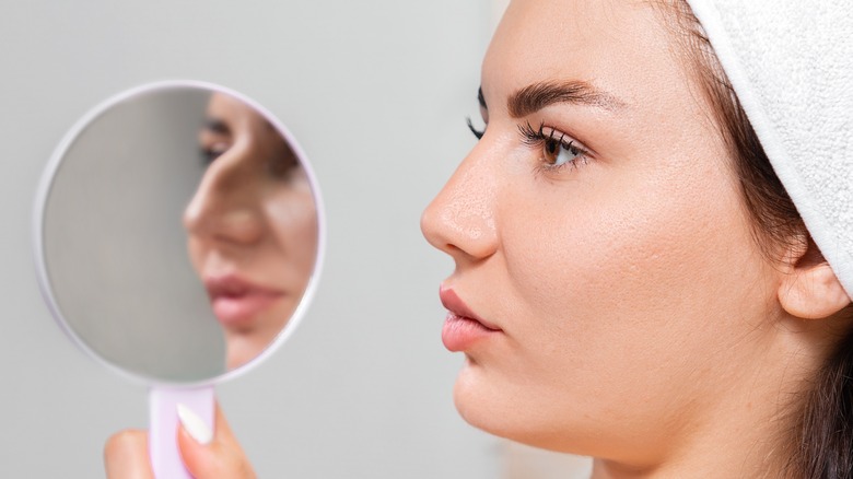 Model holding mirror to nose