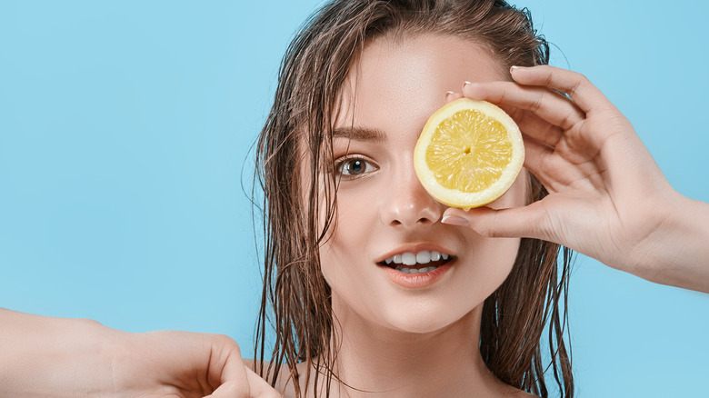 Model with wet hair holding lemon