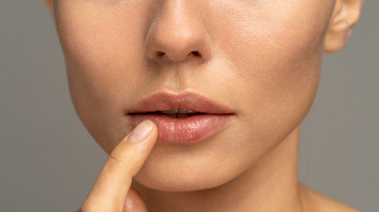 woman moisturizes lips close-up