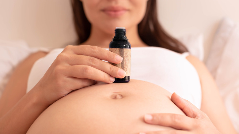 pregnant woman with a bottle of skin care product on her bump