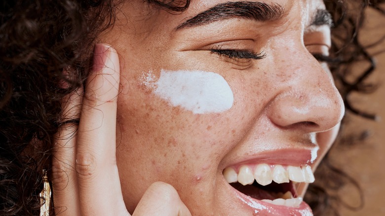 woman apply cream to face