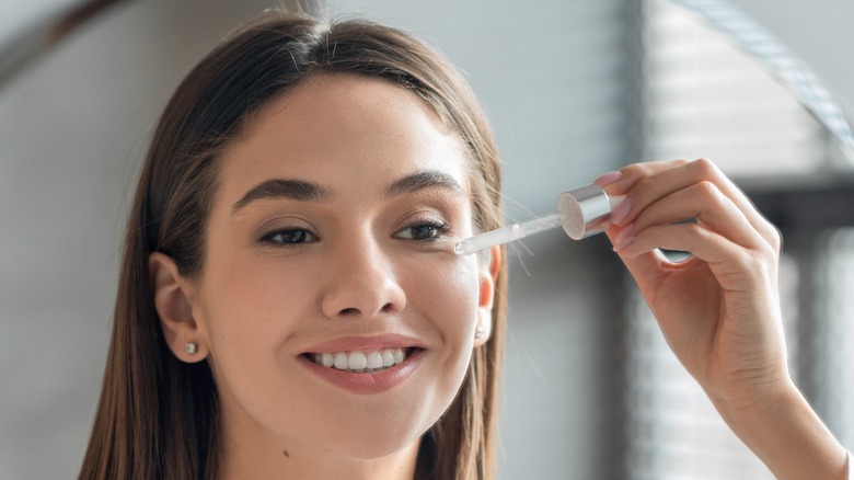 woman applying serum to face 