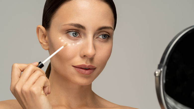 woman applying concealer under eyes