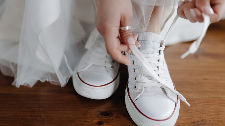 woman tying sneakers under dress