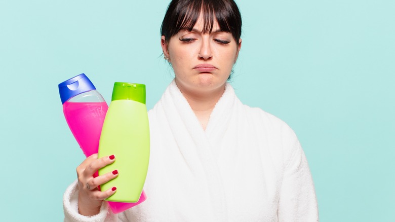 Woman frowning at shampoo bottles