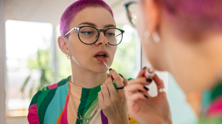 Woman applying pink lip gloss