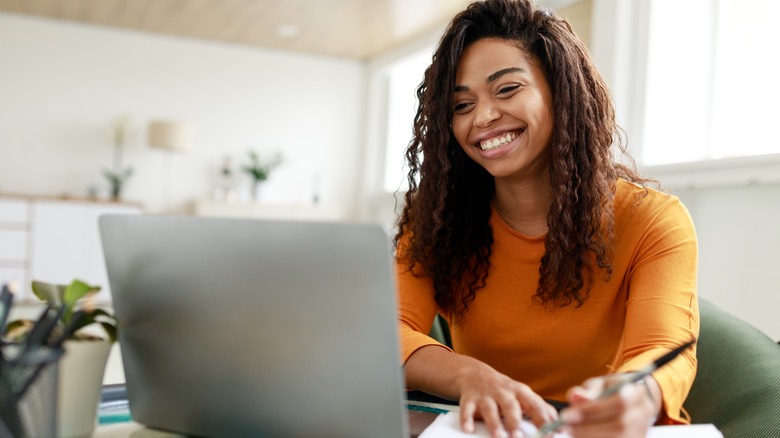 Woman seated at desk with laptop and notebook