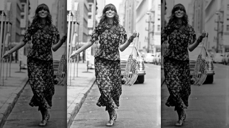 Carly Simon smiles on the street wearing a two-piece floral outfit