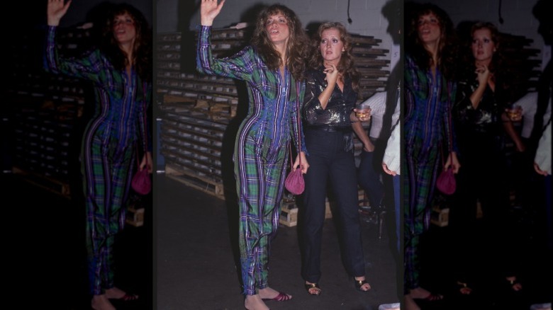 Carly Simon wearing a plaid jumpsuit for a performance, with Bonnie Raitt next to her