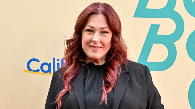 Carnie WIlson wears her red hair curled while on the carpet for an event.
