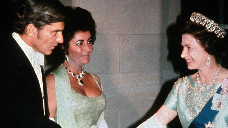 Elizabeth Taylor in a green dress with a statement necklace and earrings meeting Queen Elizabeth.