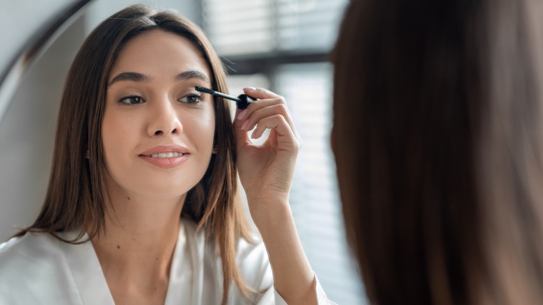 Woman applying mascara in mirror