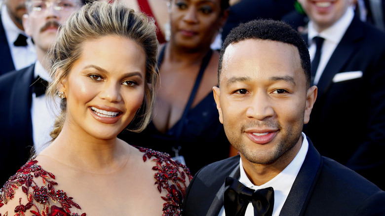 Chrissy Teigen and John Legend smiling together on a red carpet