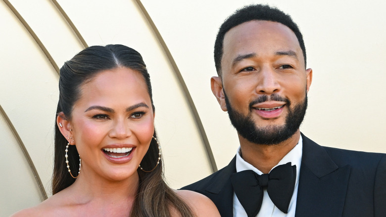 Chrissy Teigen and John Legend smiling together on a red carpet