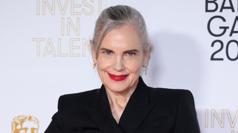 Elizabeth McGovern at a red carpet event wearing a black top with bright-red lipstick and gray hair styled in an updo.