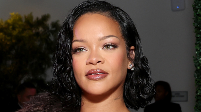 Rihanna posing with black hair and a fur coat.