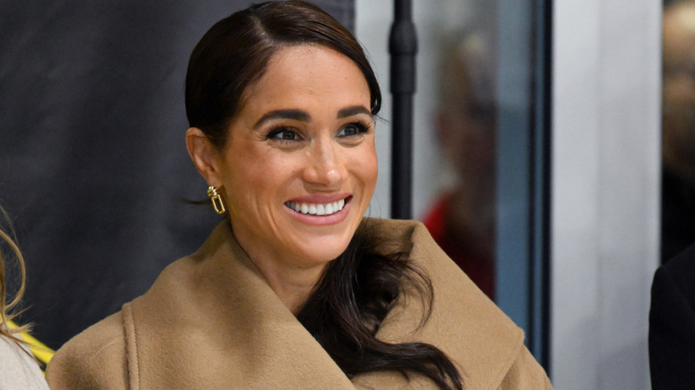 Meghan Markle smiling with her lined lips at an Invictus Games event.