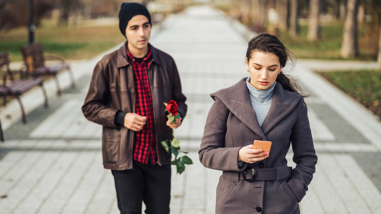 woman ignoring man with rose