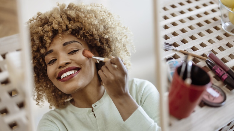 Woman applying blush in mirror