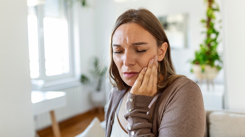 Woman holds cheek in pain