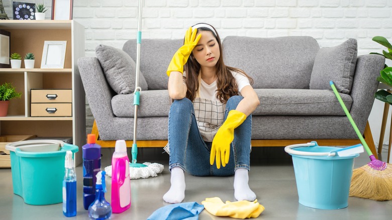 Woman sitting on floor with cleaning supplies