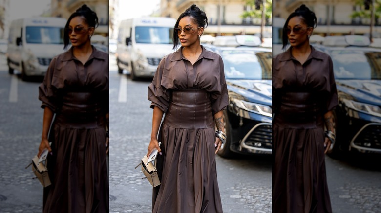 A woman wearing a brown maxi skirt with a cinched in waist and a baggy shirt