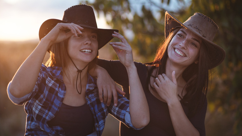two cowgirls outside during a sunset