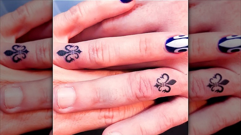 couple with fleur de lis ring finger tattoos