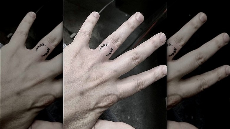 person with laurel wreath wedding ring tattoo