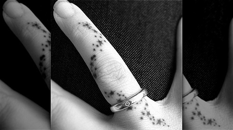 person with dots stars ring finger tattoo